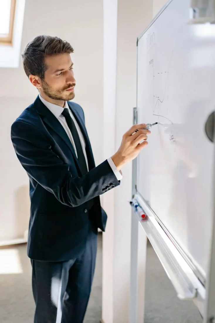 homme en train d'écrire sur un tableau lors d'un séminaire